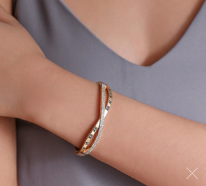 Gold-tone roman numeral bracelet bangle with rhinestone trim worn on wrist