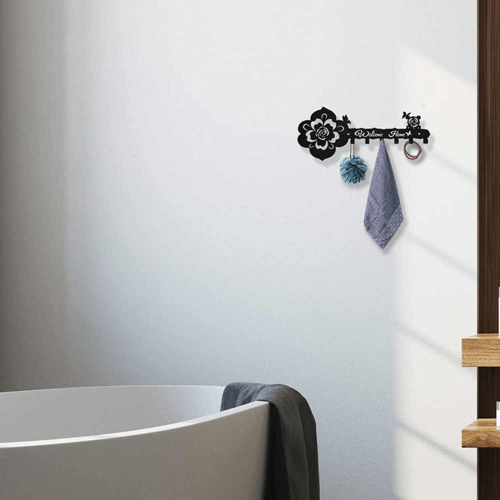 Black rose-pattern key hanger on wall with four hooks and hanging towel