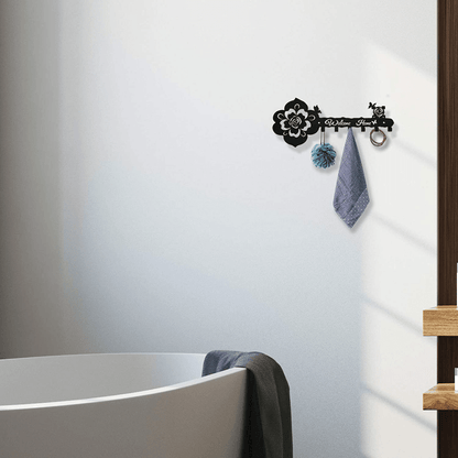 Black rose-pattern key hanger on wall with four hooks and hanging towel