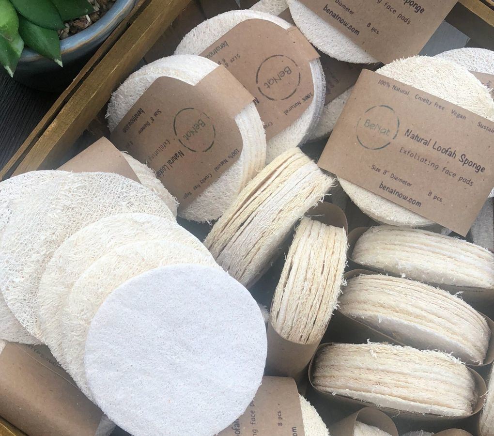Loofah sponge pads in kraft packaging, multiple round beige discs.