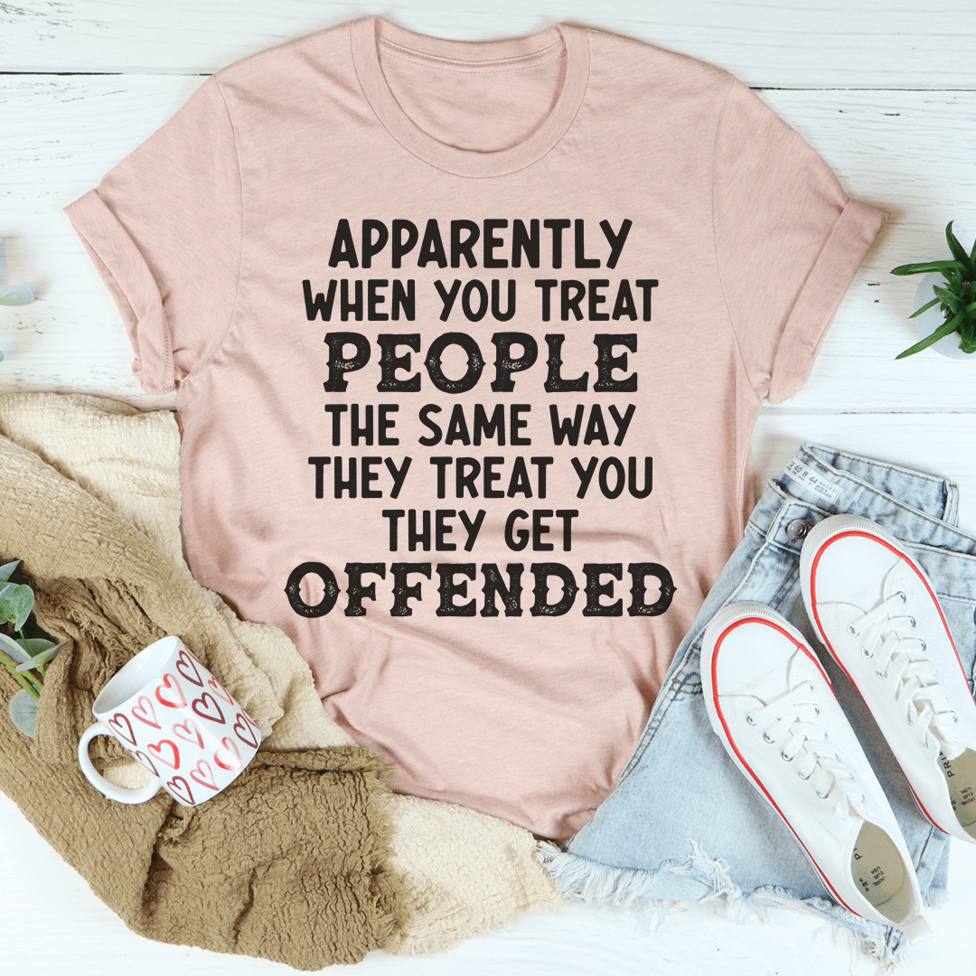 Light mauve crewneck T-shirt with bold 'APPARENTLY' to 'OFFENDED' slogan print