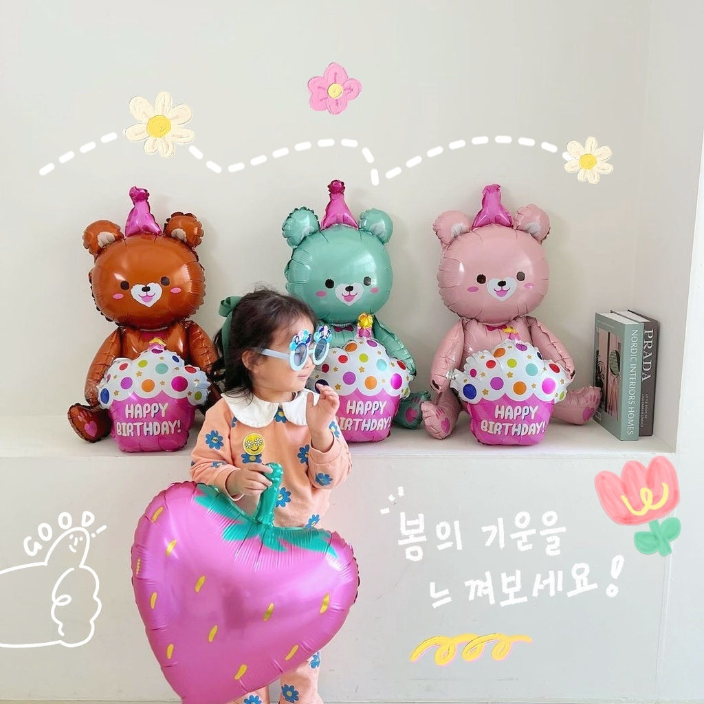 Three bear foil balloons on wall display: orange, teal, and pink, each with "Happy Birthday"