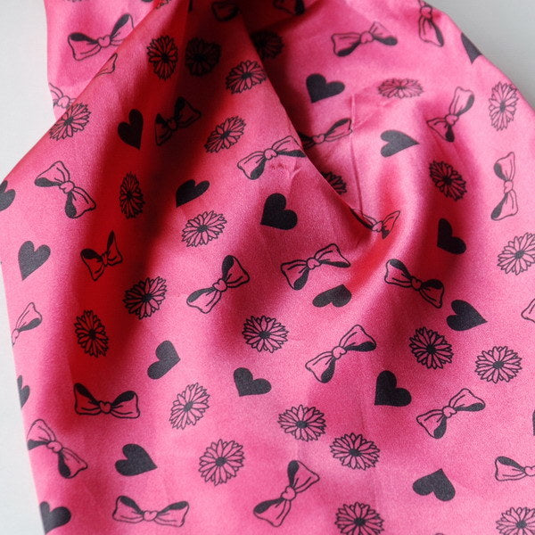 Pink silk scarf close-up with hearts, flowers, bows and butterflies pattern