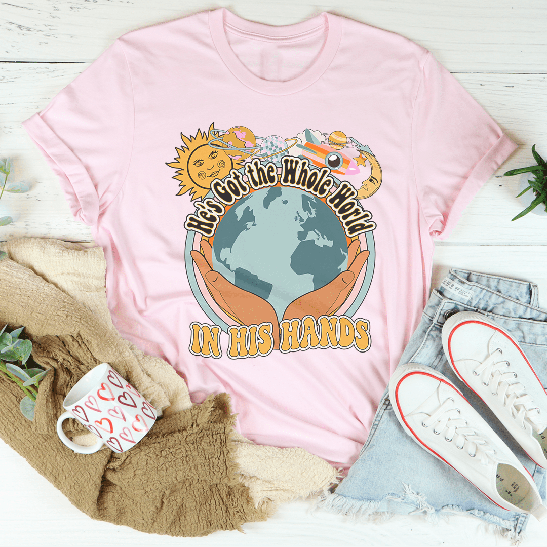 Pink T-shirt with globe graphic held in hands and “IN HIS HANDS” text
