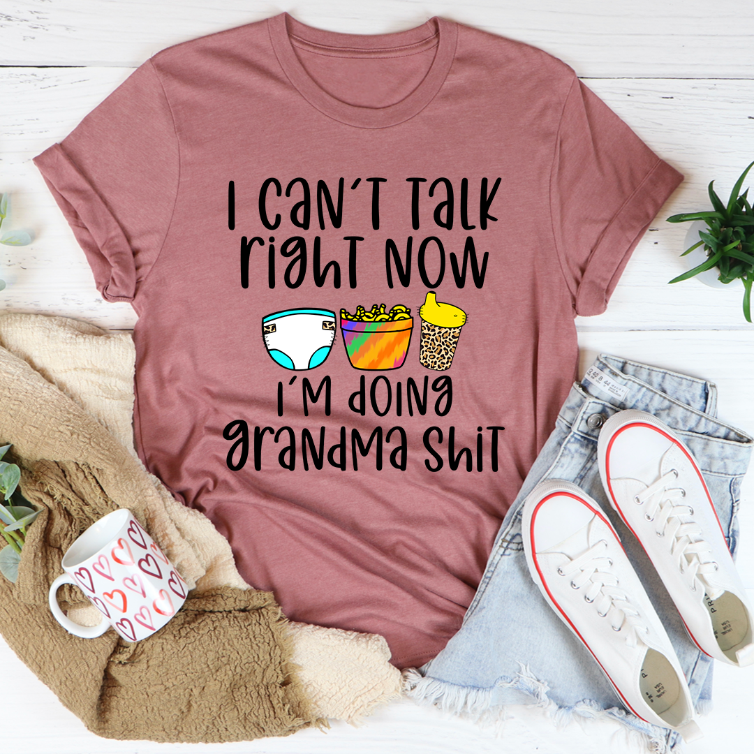 Mauve T-shirt with “I CAN'T TALK RIGHT NOW” slogan and colorful icons graphic at center.