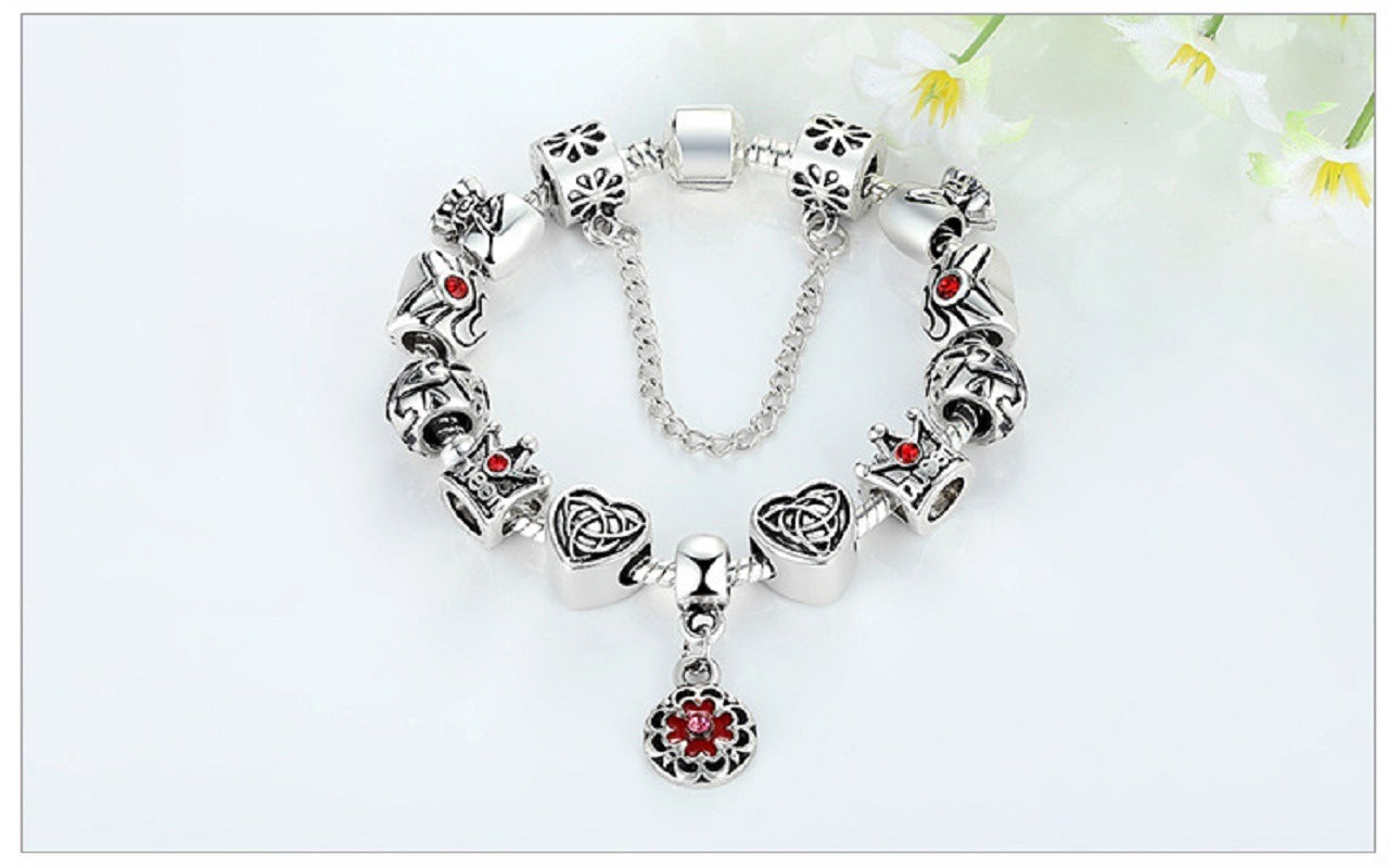 Silver charm bracelet with red enamel flower pendant and bead charms, with chain link