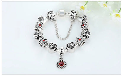 Silver charm bracelet with red enamel flower pendant and bead charms, with chain link