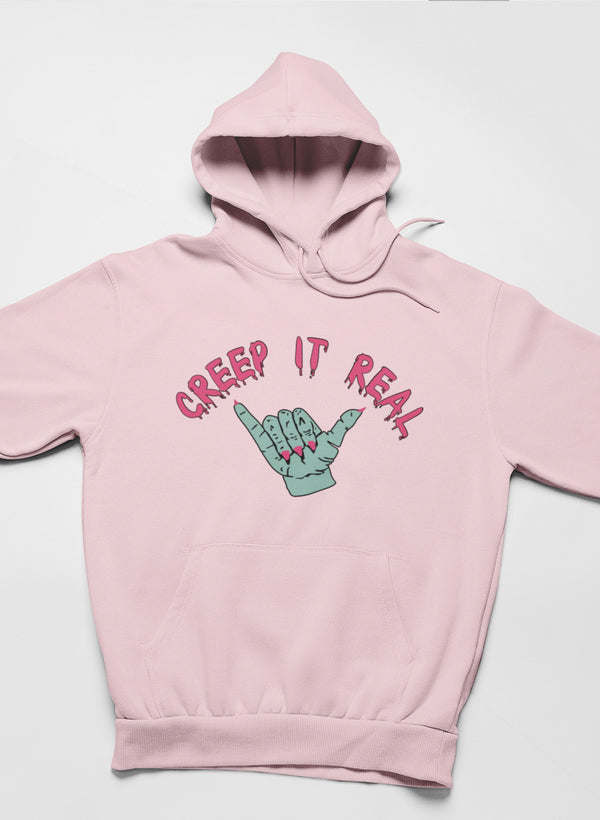 Pink hoodie with front hood and hand graphic reading “Creep It Real”.