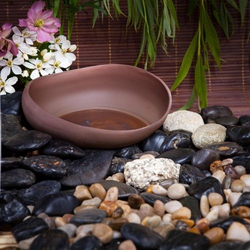 Polished black river rocks with light stones around a shallow bowl planter decor