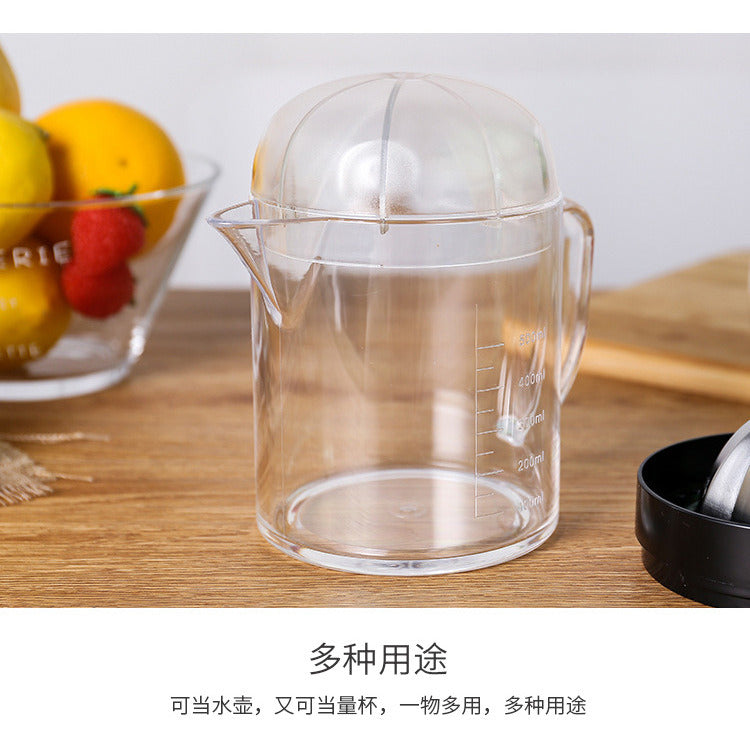 Clear citrus juicer pitcher with measuring markings and handle, with black strainer part nearby