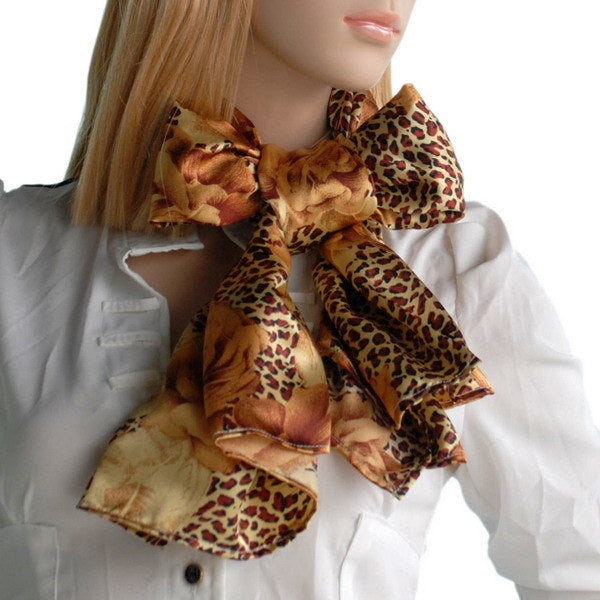 Gold leopard print silk scarf with rose floral bows, styled at collar
