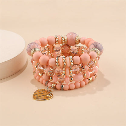Layered charm bracelet set with pink beads, gold charms, and heart pendant