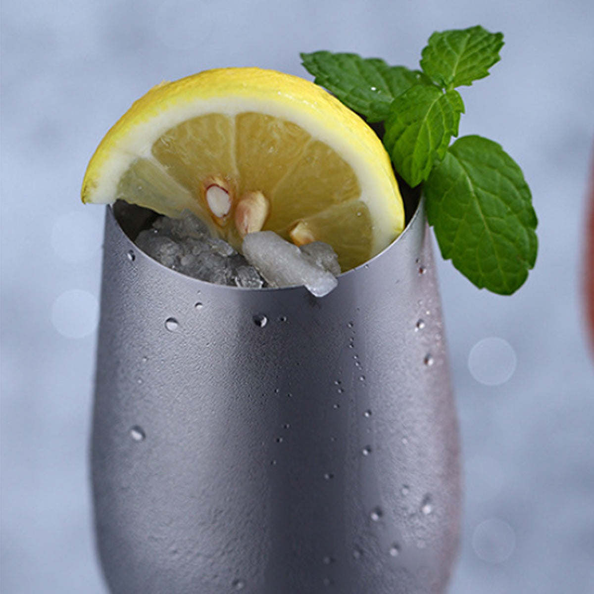 Silver metallic drink glass with lemon wedge and mint leaves on top