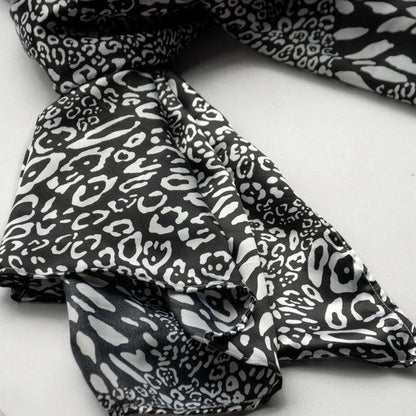 Small leopard-print silk scarf, black-and-white pattern with visible folds and knot