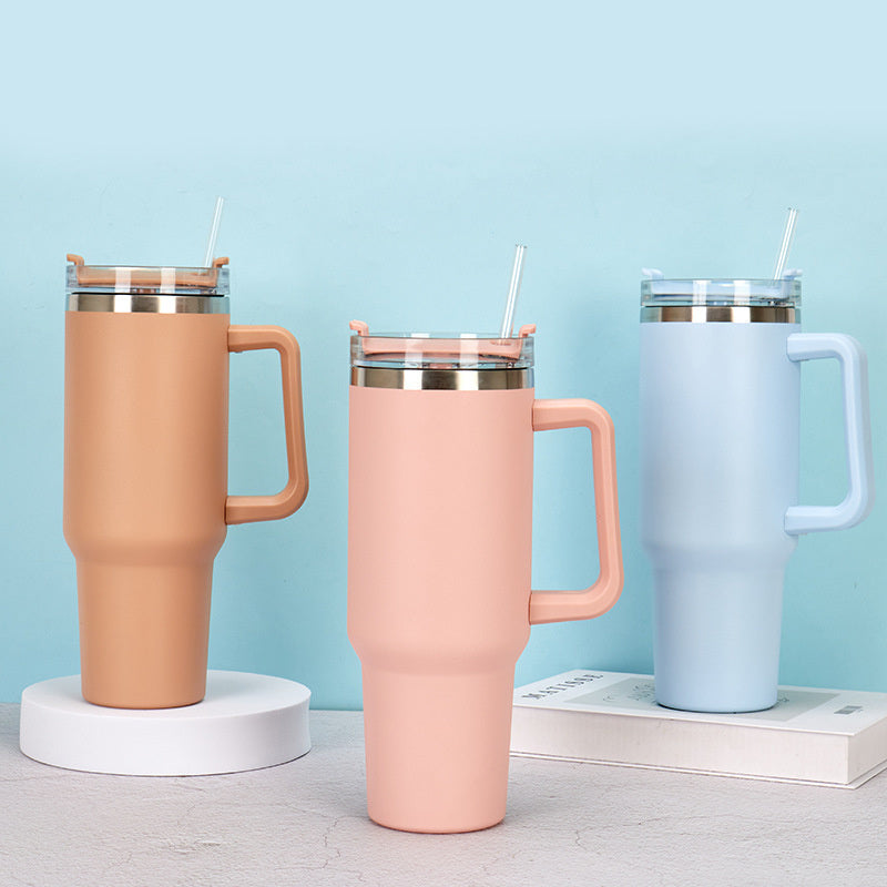 Vacuum tumbler with orange finish, handle, and clear straw lid
