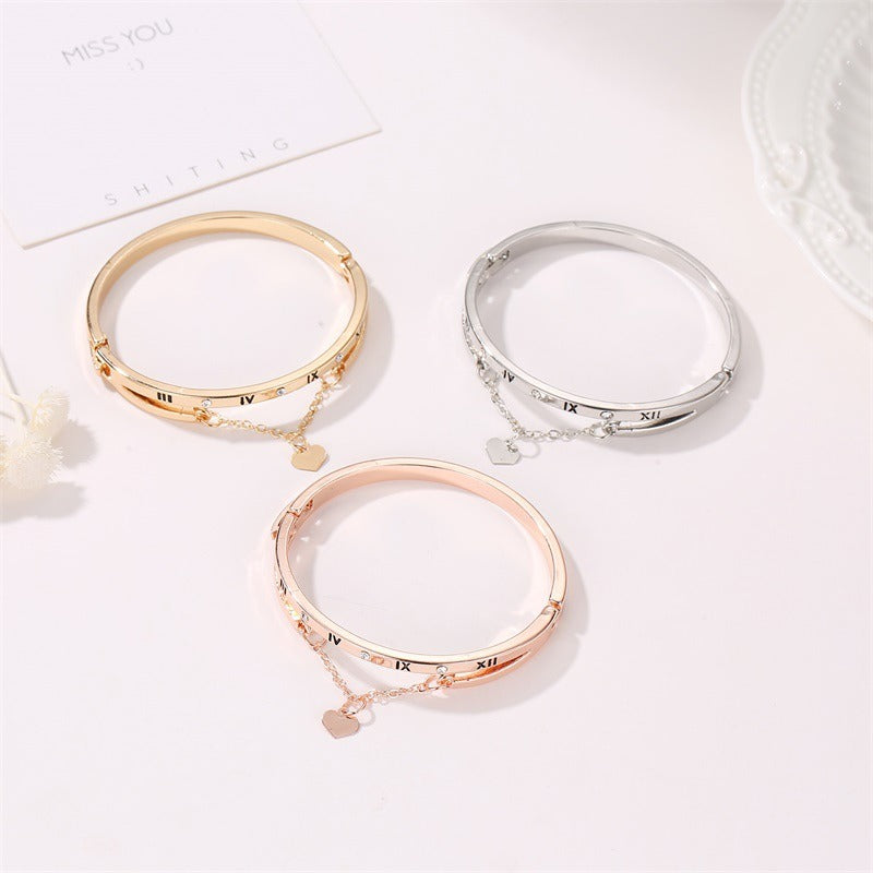 Three bangle bracelets: gold, rose gold, and silver with roman numerals and heart charms