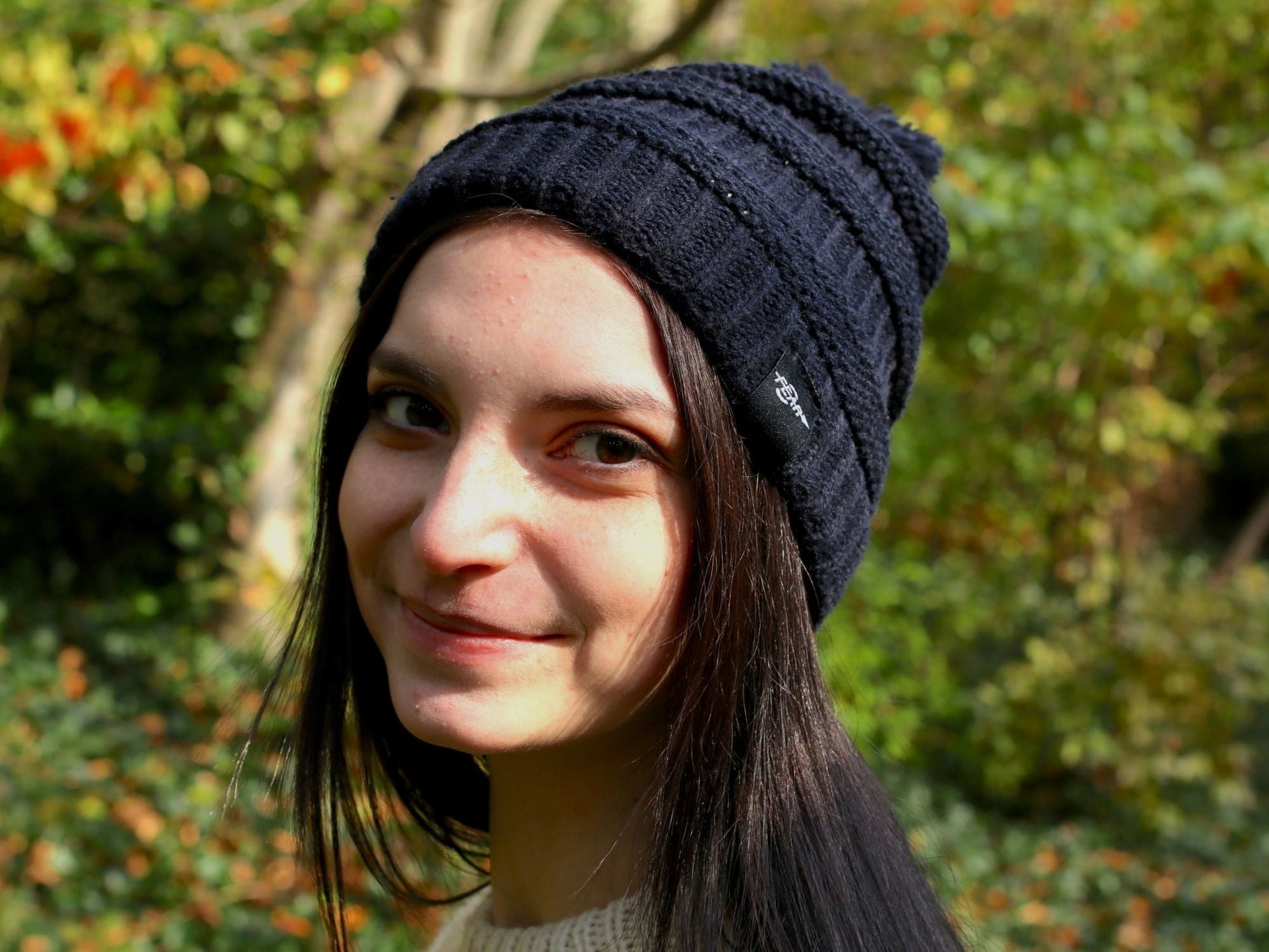 Black cable knit beanie with pom-pom on model, ribbed brim