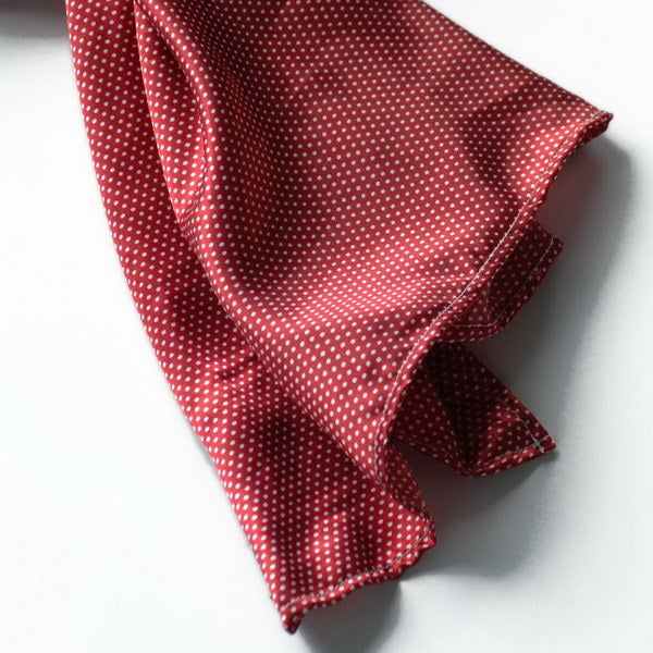 Red silk scarf close-up with small white dots and soft draped folds