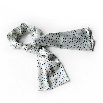 Large silk scarf in white with small black dot print, loosely knotted ends.