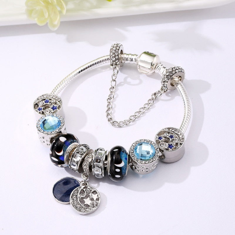 Silver-tone charm bracelet with blue crystal charms, black beads, and two hanging discs
