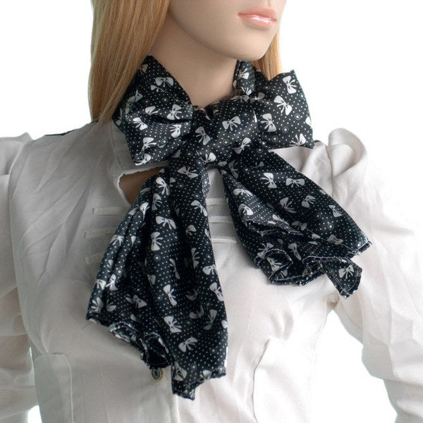 Black silk scarf with white motifs and ruffled bow tie, worn around neck