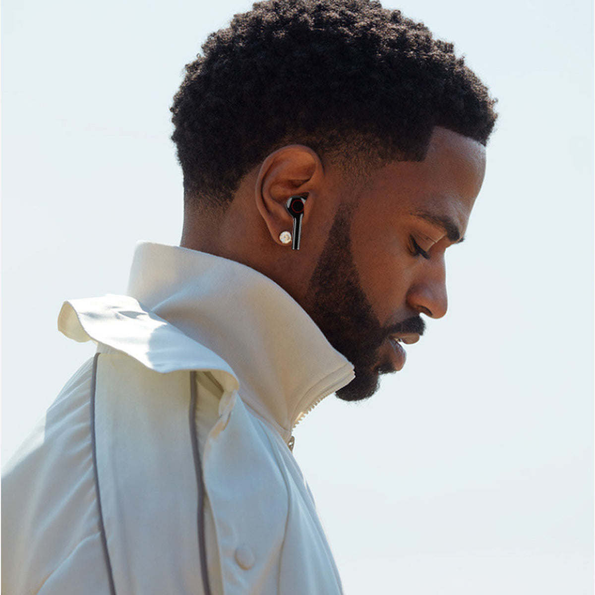 Black wireless Bluetooth earbuds in-ear on man, side profile
