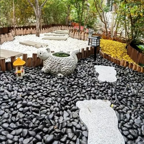 Polished black river rocks covering a garden yard with white stepping stones