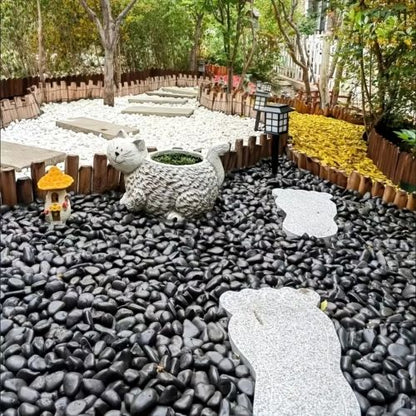 Polished black river rocks covering a garden yard with white stepping stones