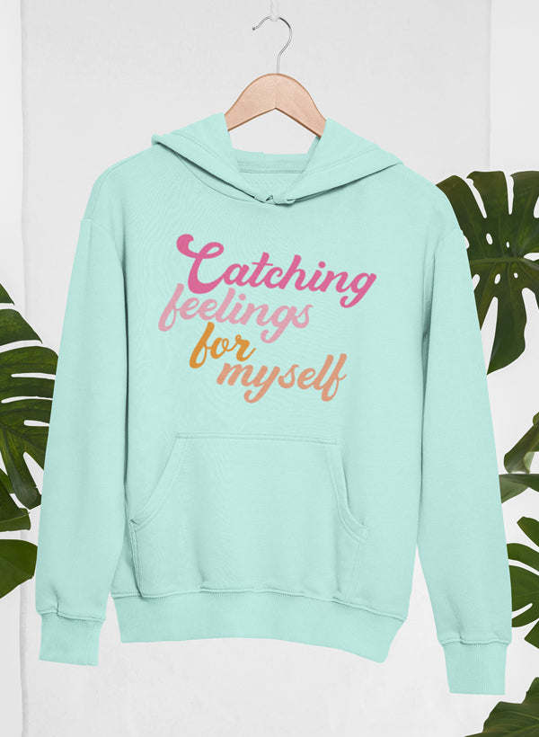 Light blue hoodie with 'Catching feelings for myself' print, hood, and kangaroo pocket