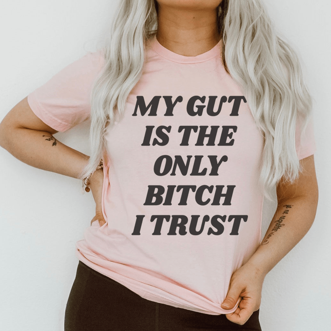 Pink T-shirt worn by model with dark front slogan: MY GUT IS THE ONLY BITCH I TRUST