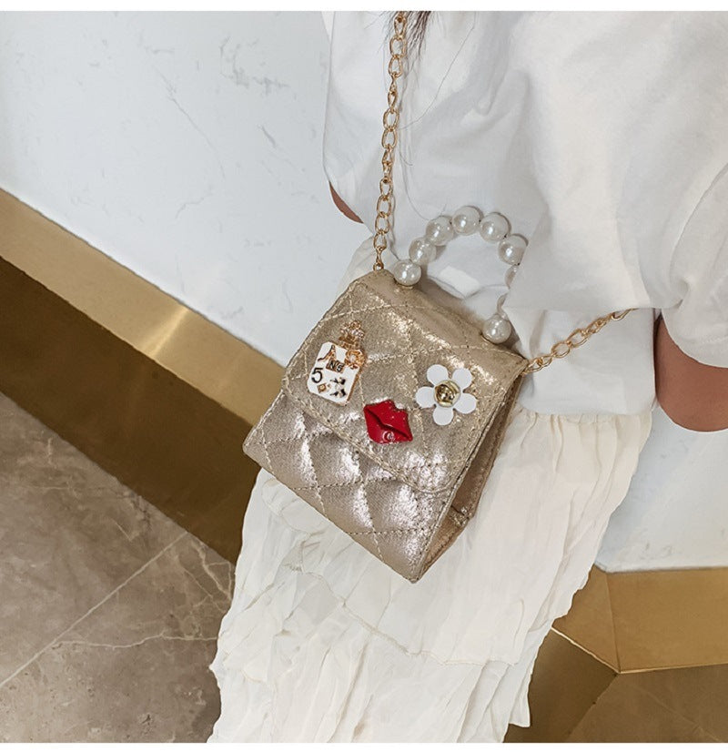 Gold mini quilted crossbody bag with pearl top handle and decorative charm front