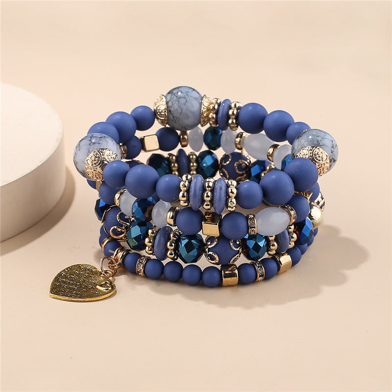 Layered bead bracelet set with blue beads, gold charms, and heart charm pendant