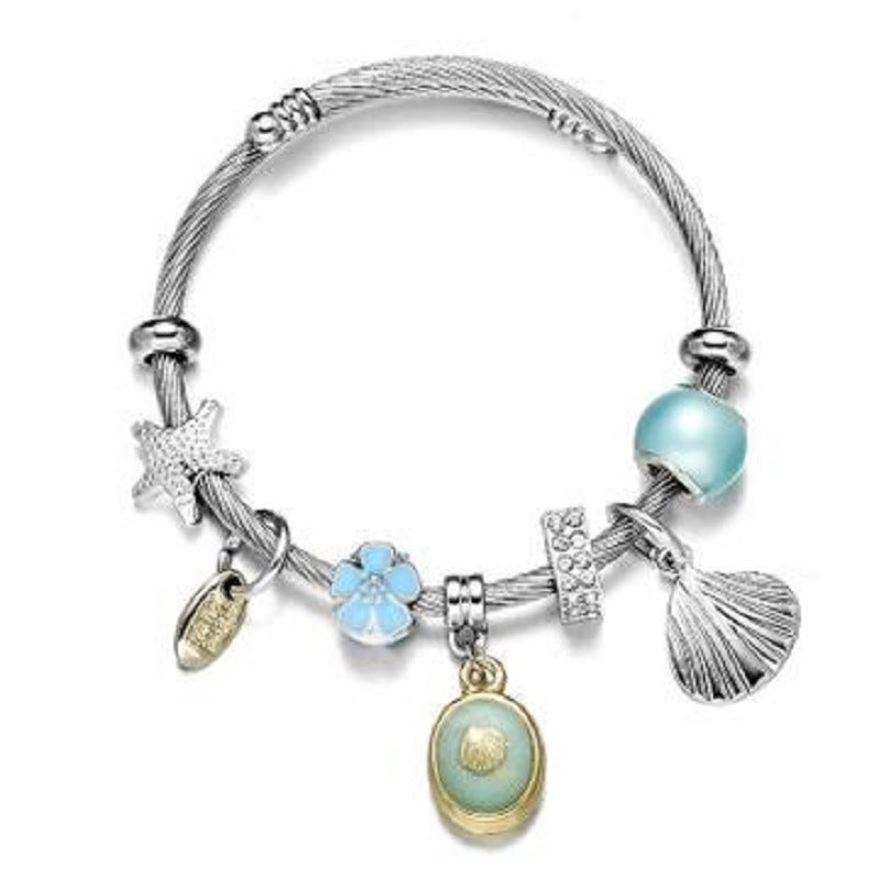 Silver wrap bangle bracelet with blue bead, flower, fan shell, and oval shell charm