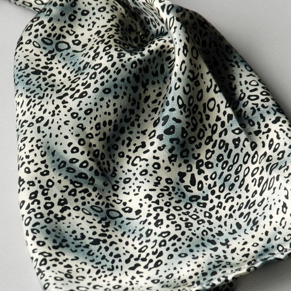 Leopard-print silk fabric close-up with scattered small spots in light and dark tones