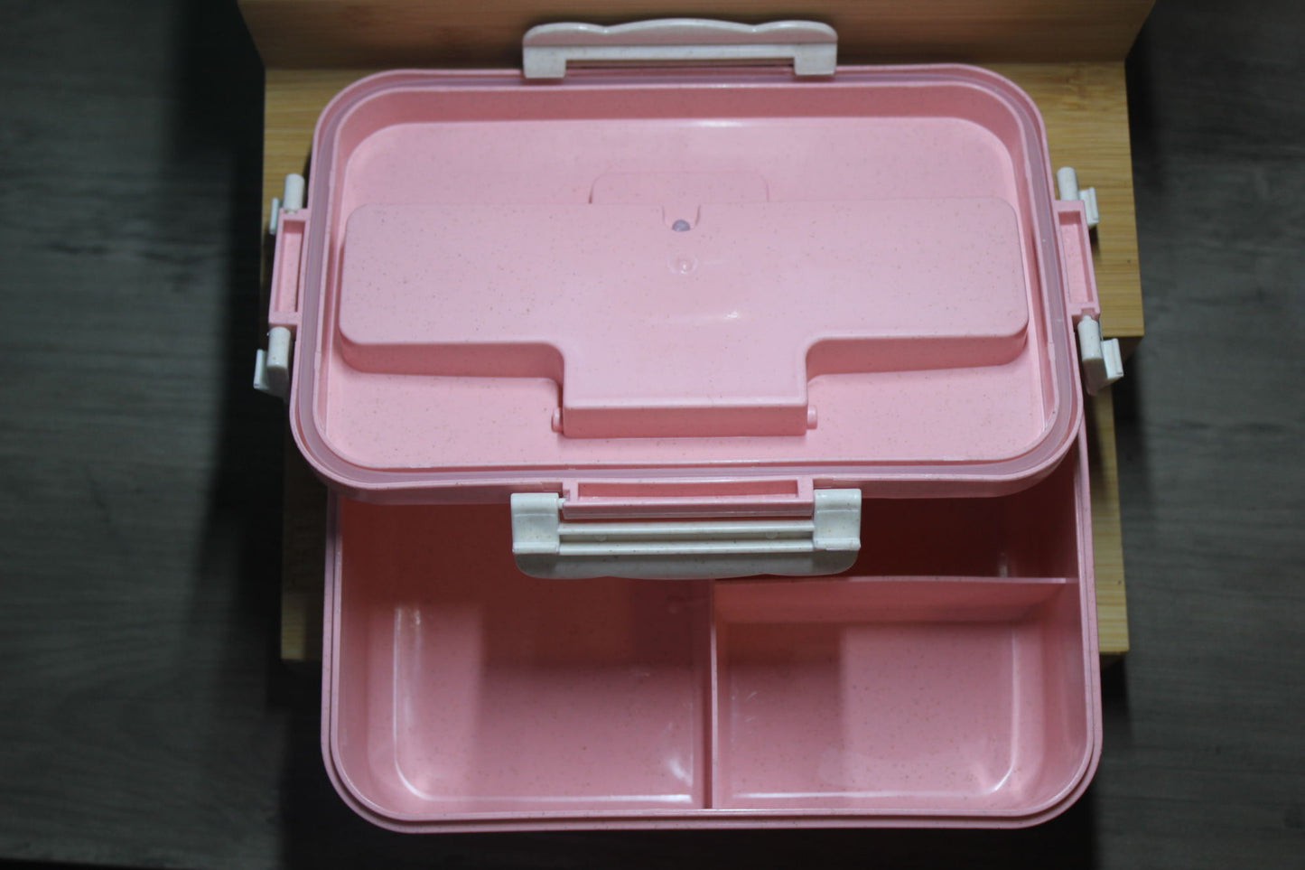 Pink bento box closed with lid and two-section interior