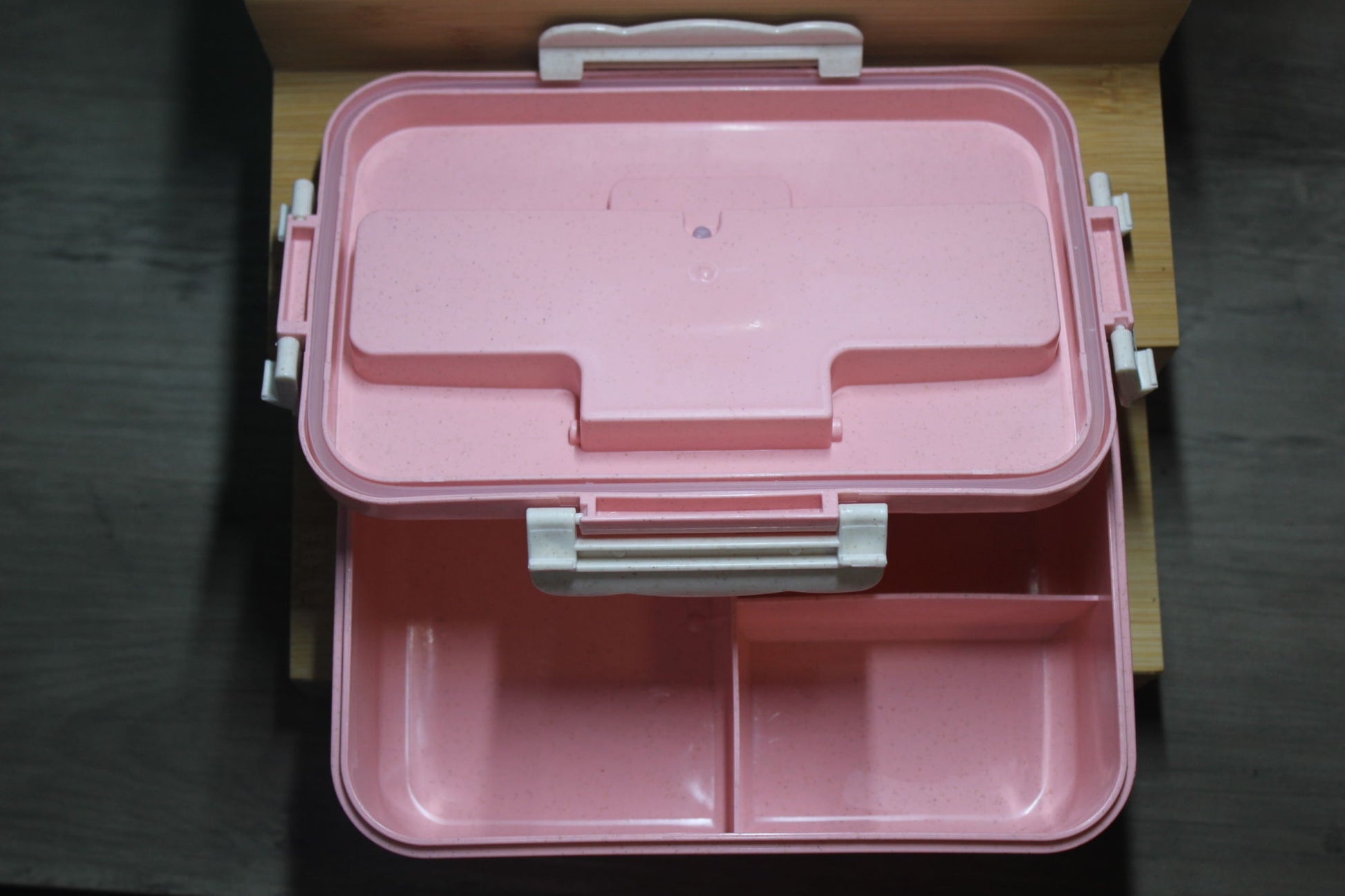 Pink bento box closed with lid and two-section interior