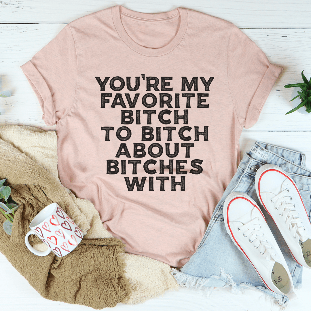 Peach-pink graphic T-shirt with bold slogan text on crew neck, short sleeves