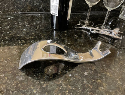 Sculpted chrome bottle holder with open center and curved wave base