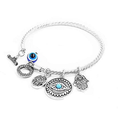 Twisted charm bracelet with evil eye and hamsa charms, blue enamel accents, silver-tone finish.