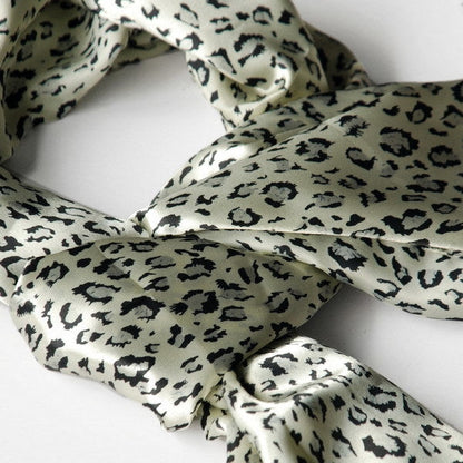 Silk scarf close-up with ivory background and dark leopard pattern.