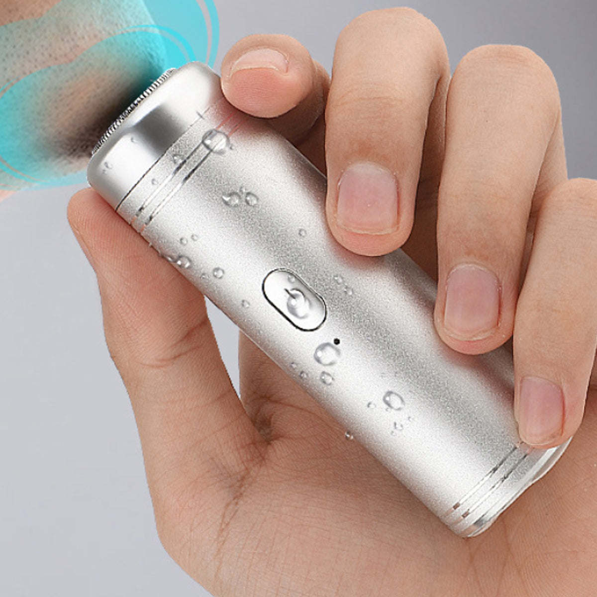 Silver mini electric shaver with water droplets and power button, held in hand