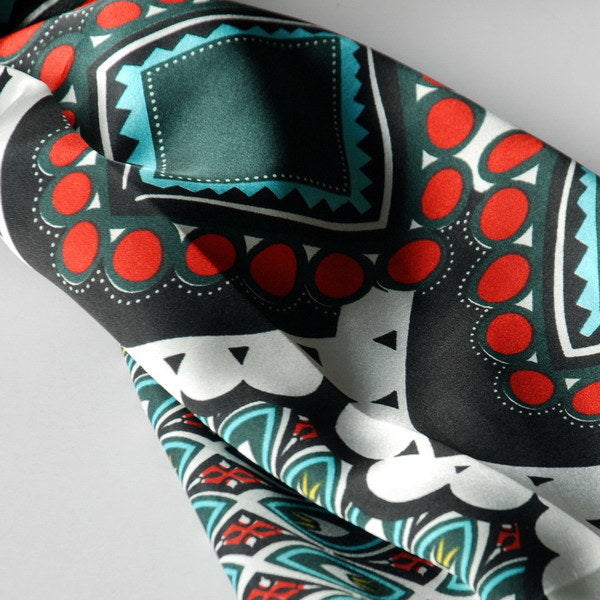 Close-up of dark green scarf fabric with red dots and teal geometric panels
