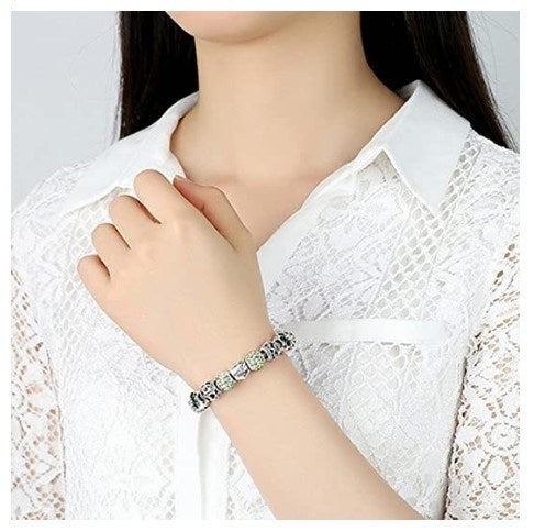 Silver-tone charm bracelet with blue flower beads and heart Love charm on wrist.