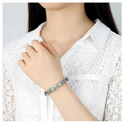 Silver-tone charm bracelet with blue flower beads and heart Love charm on wrist.
