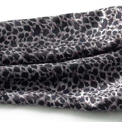 Close-up of leopard-print silk scarf fabric with dark purple and black tones