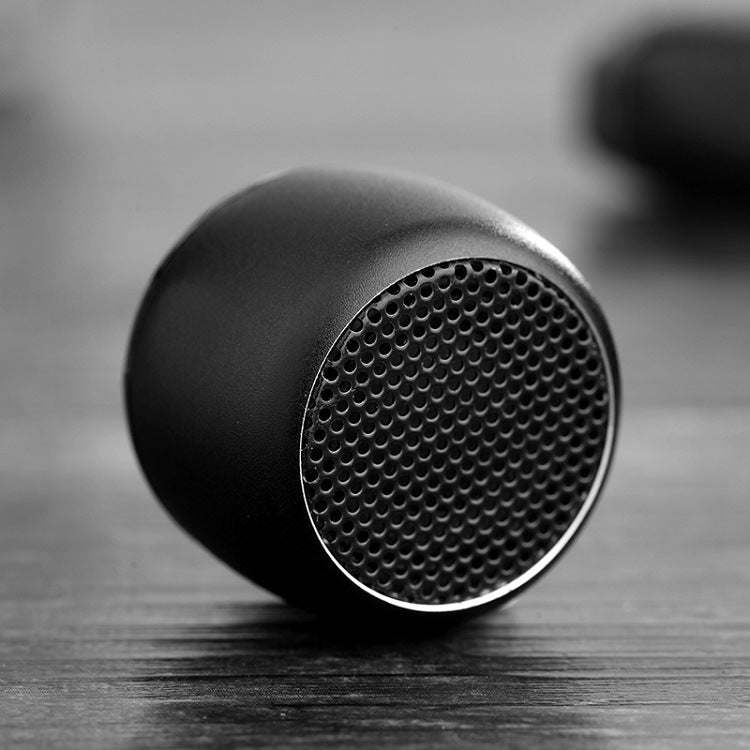 Black Bluetooth speaker side view with circular grille and smooth, textured body
