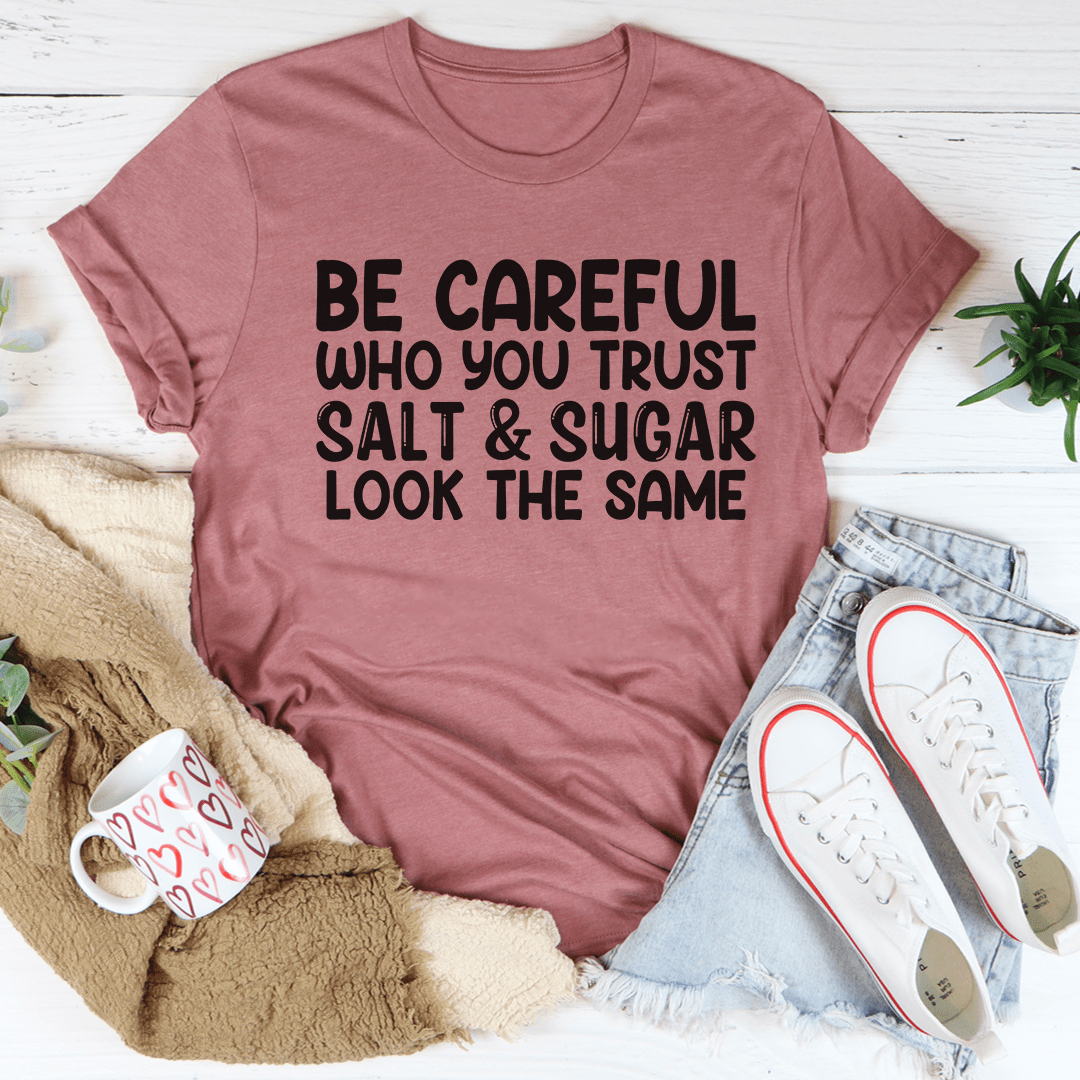 Pink T-shirt with “BE CAREFUL” stacked text slogan graphic in black