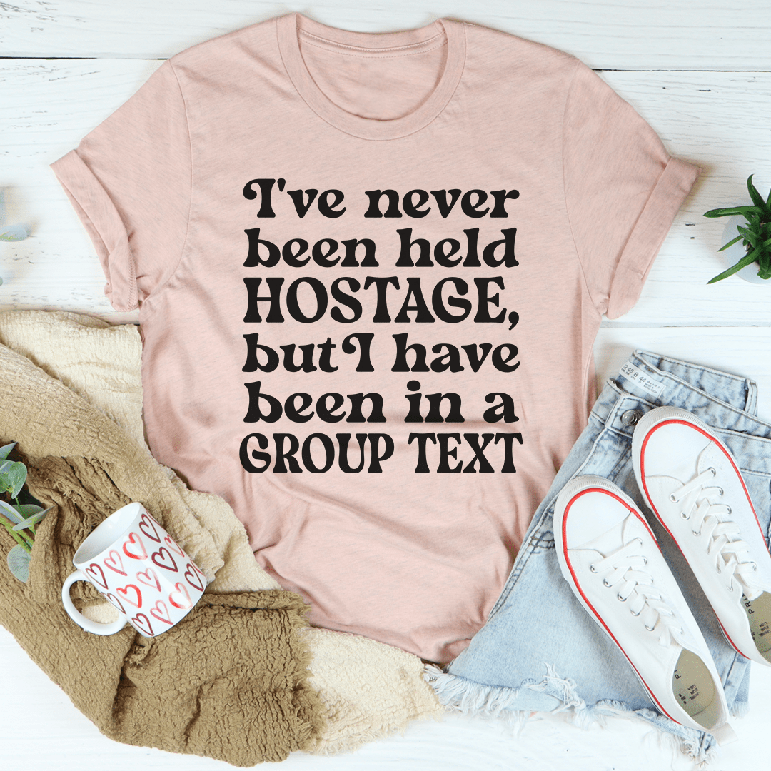 Light pink graphic T-shirt with bold black 'HOSTAGE' and 'GROUP TEXT' text block