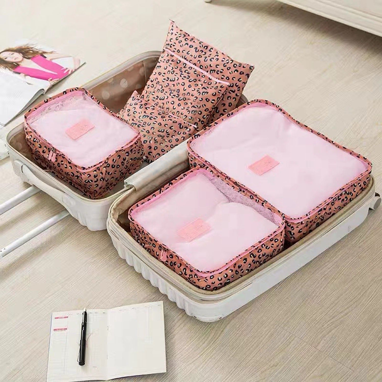 Leopard print packing cubes with pink accents and zippered compartments on luggage