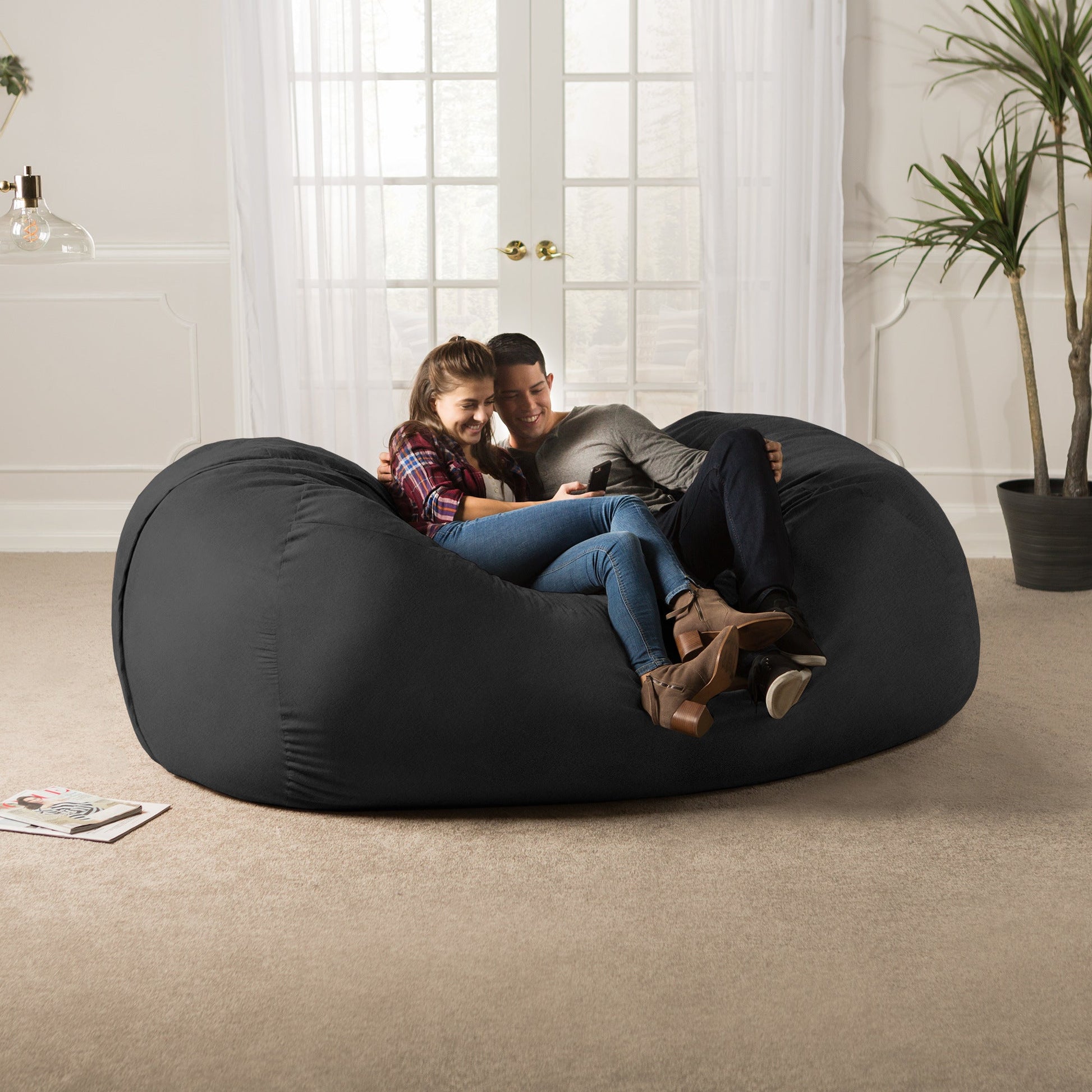 Black giant bean bag sofa with two people cuddling on the beanbag cushion